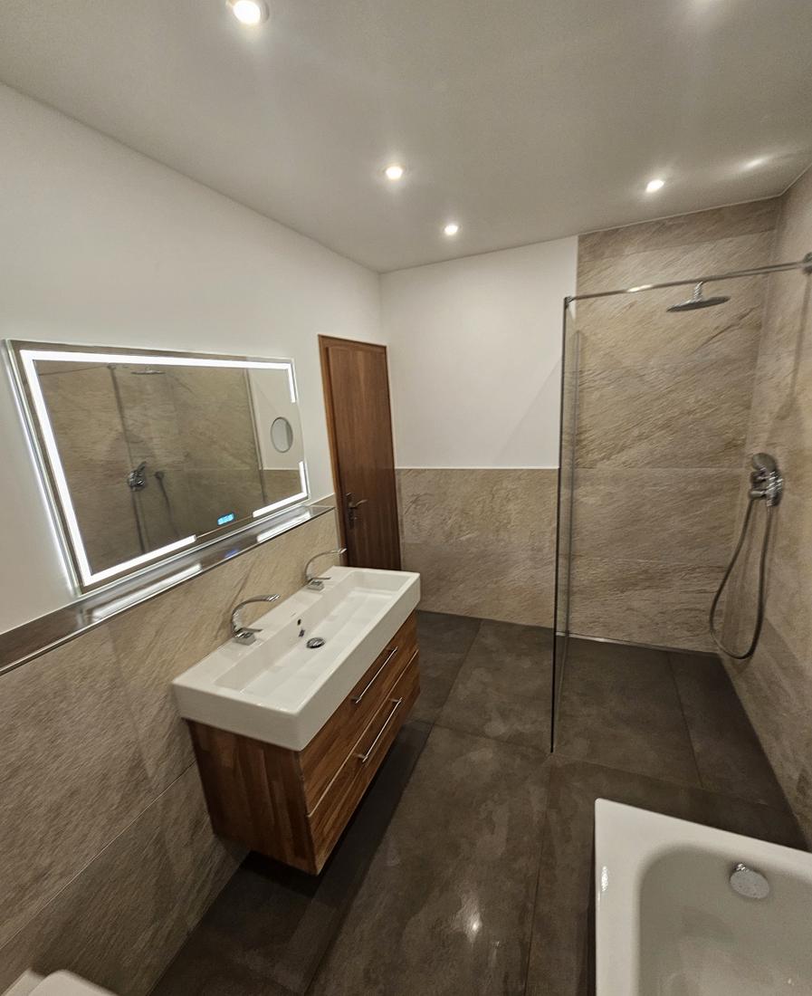 Walk-in-Dusche mit Wandfliesen in Steinoptik und Doppelwaschtisch