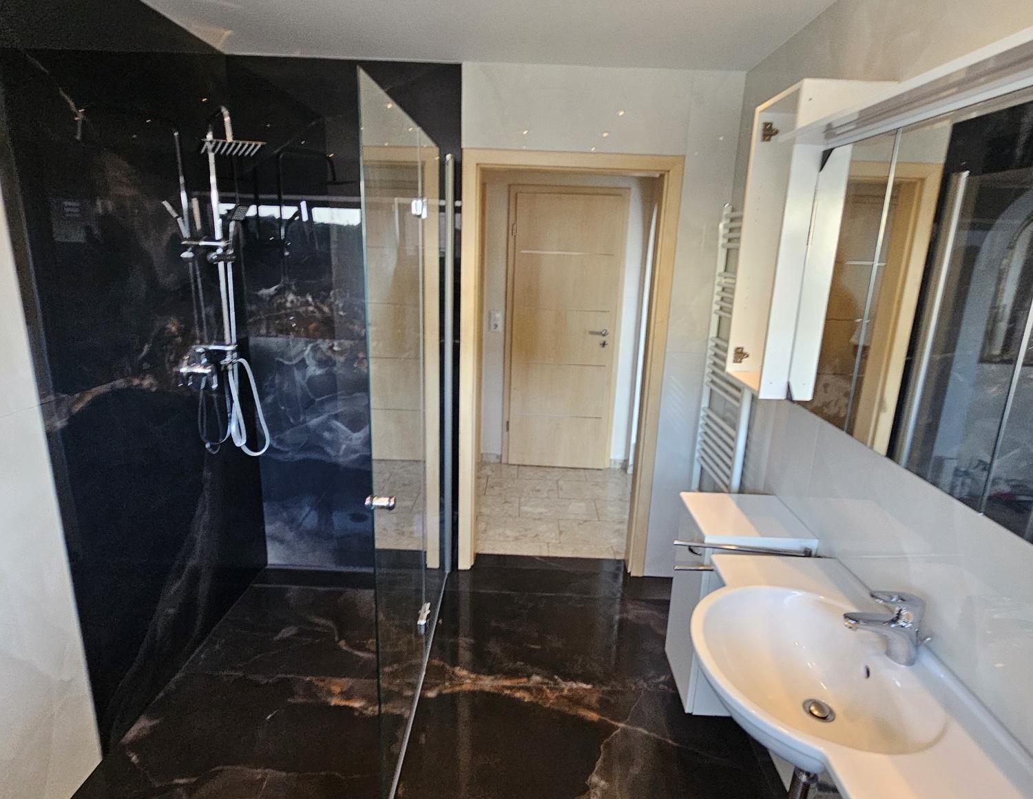 Bad mit großformatigen Fliesen in schwarzer Marmoroptik und Walk-in-Dusche