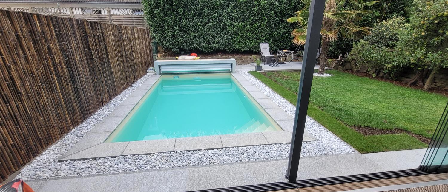 Poolumrandung mit hellen Platten und Kiesstreifen
