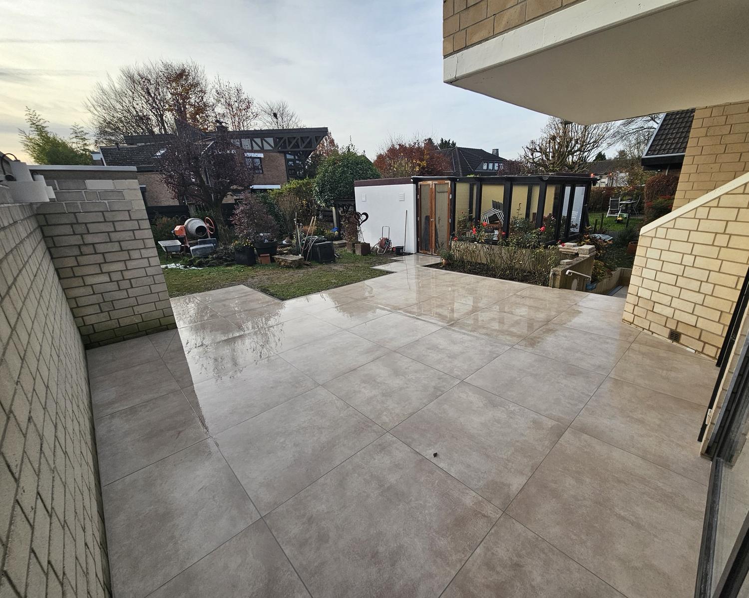 Großformatige Terrassenplatten nach Regen, mit Blick in den Garten