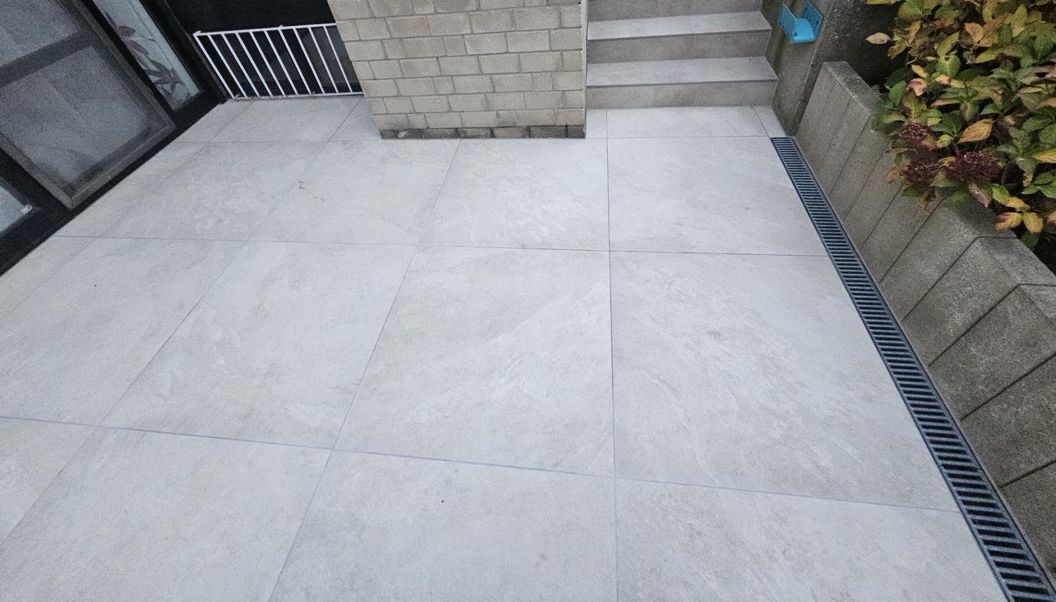 Terrasse mit großformatigen Platten, Stufen und Entwässerungsrinne